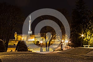 Victor statue on Kalemegdan fortress seen from the Kalemegdan park during a cold winter evening, covered in snow.