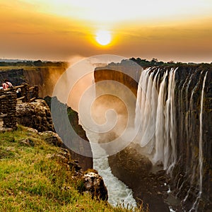 Victoria falls sunset with orange sun and tourists