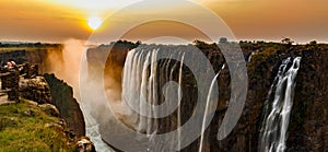 Victoria falls sunset panorama with orange sun and tourists