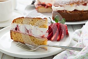 Victoria sponge cake filled with whipped cream, jam and fresh strawberries in a dish