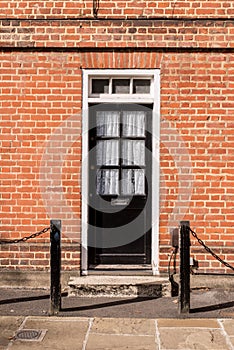 Victorian black external wooden door with glass panels on a classic red brick wall