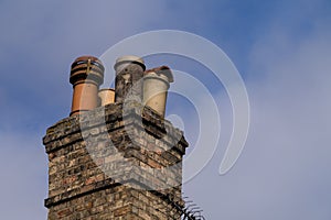 Victorian domestic chimney with four assorted chimney-pots against a clear blue sky background. Copy space