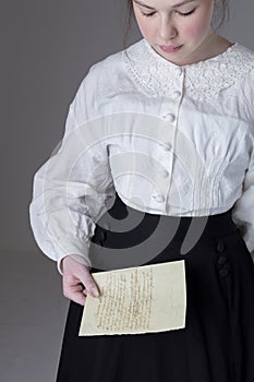 A Victorian or Edwardian woman wearing a white linen garibaldi blouse and black skirt