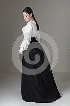 A Victorian or Edwardian woman wearing a white linen garibaldi blouse and black skirt