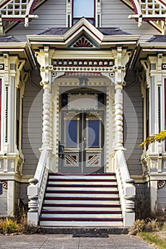 Victorian era gingerbread trimmed home entrance with steps up to front door and painted bric a brac