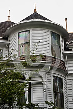 Victorian home with focus on round turret with bay windows and porch