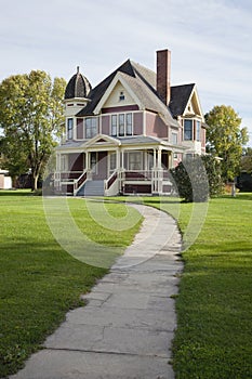 Victorian house with lawn and sidewalk on sunny afternoon