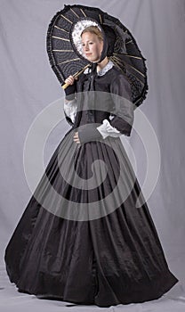Victorian woman in a black bodice, skirt, parasol and bonnet