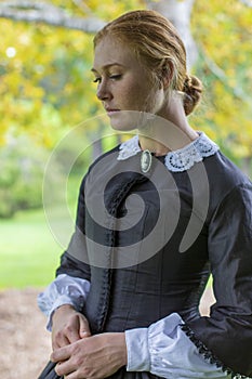 Victorian woman in black dress walking in garden