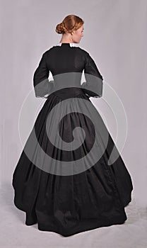 Victorian woman in black ensemble  on studio backdrop