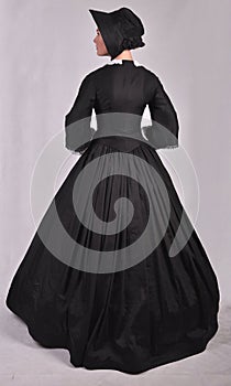 Victorian woman in black ensemble  on studio backdrop