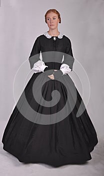Victorian woman in black ensemble  on studio backdrop photo