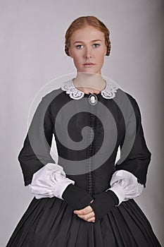 Victorian woman in black ensemble  on studio backdrop photo