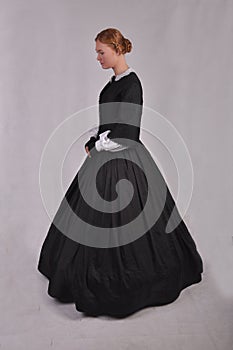 Victorian woman in black ensemble  on studio backdrop photo