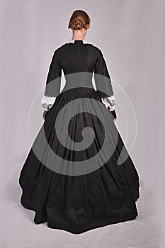 Victorian woman in black ensemble  on studio backdrop