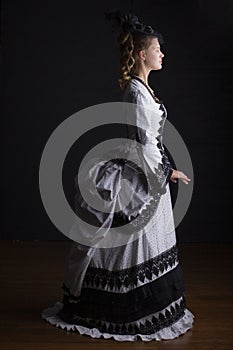 Victorian woman in black and white bustle dress and hat