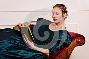 Victorian woman laying on couch reading book