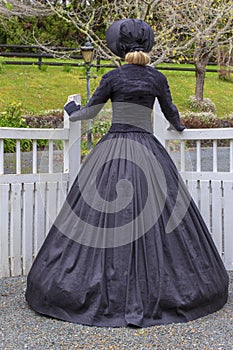 Victorian woman in summer garden and opening a gate