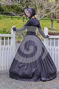 Victorian woman in summer garden and opening a gate