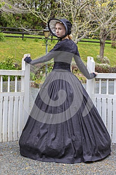 Victorian woman in summer garden and opening a gate