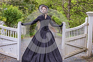 Victorian woman in summer garden opening a gate