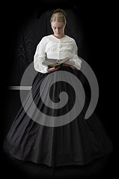 A Victorian woman with a tortoise shell comb in her hair is reading a book