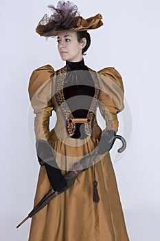 A Victorian woman wearing a bronze and brown silk ensemble