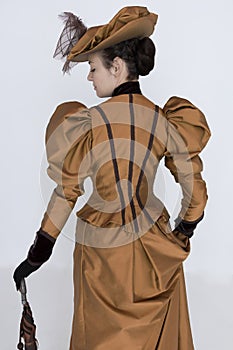 A Victorian woman wearing a bronze and brown silk ensemble