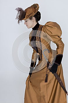 A Victorian woman wearing a bronze and brown silk ensemble