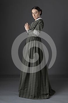 A Victorian woman wearing a dark green check bodice and skirt with a lace collar photo