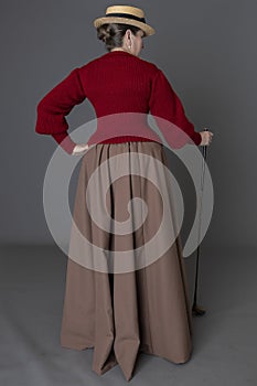 A Victorian woman wearing a golfing ensemble with a straw boater hat