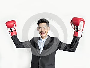 Victorious businessman raising hands with boxing gloves