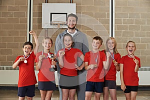 Victorious School Sports Team With Medals And Trophy In Gym