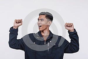 A victorious young Filipino man pumping his fist in elation. Isolated on a white background