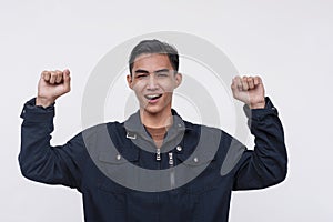 A victorious young Filipino man pumping his fist in elation. Isolated on a white background