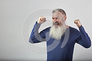 Victory concept, anger and discontent, portrait of mature gray-haired bearded man on gray background, selective focus