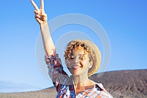 Victory hand gesture to stop war and love peace for people concept image with happy adult woman in the country side, smiling and