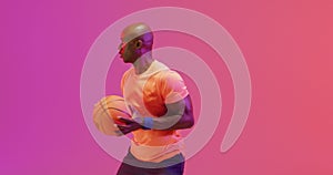 Video of african american male basketball player throwing ball on pink to orange background