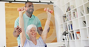 Video of african american male physiotherapist exercising with caucasian senior woman