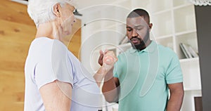 Video of african american male physiotherapist exercising with caucasian senior woman