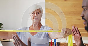 Video of african american male physiotherapist exercising with caucasian senior woman