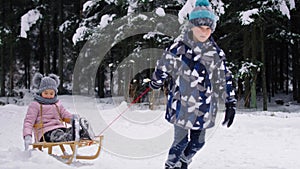 Video of boy pulling sledge with little sister in snow.