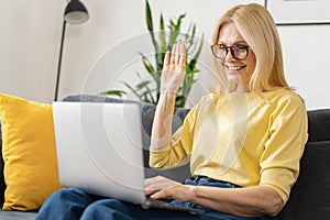 Video call concept. Happy senior woman using laptop computer for video connection from home, mature female looks at