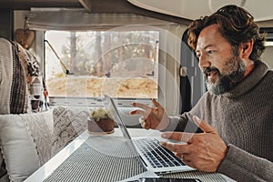 Video call conference in freedom office workplace lifestyle. One man speaking with internet and laptop inside a camper van parkied