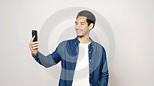 Video call conference, Happy asian man having a video chat on mobile phone while standing on grey background, Asia male talking