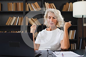 Video call. Happy middle aged senior woman sit with laptop talk on video call. Mature old senior lady having fun talking