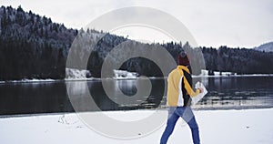 Video capturing amazing landscape view of a big lake and snowy forest , tourist walking around to the shore lake in a