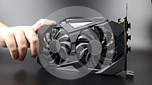 the video card is held by a teenager& x27;s hand on a black matte background. there are places for text. new technologies