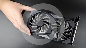 the video card is held by a teenager& x27;s hand on a black matte background. there are places for text. new technologies