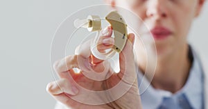 Video of caucasian female doctor holding hearing aid, selective focus